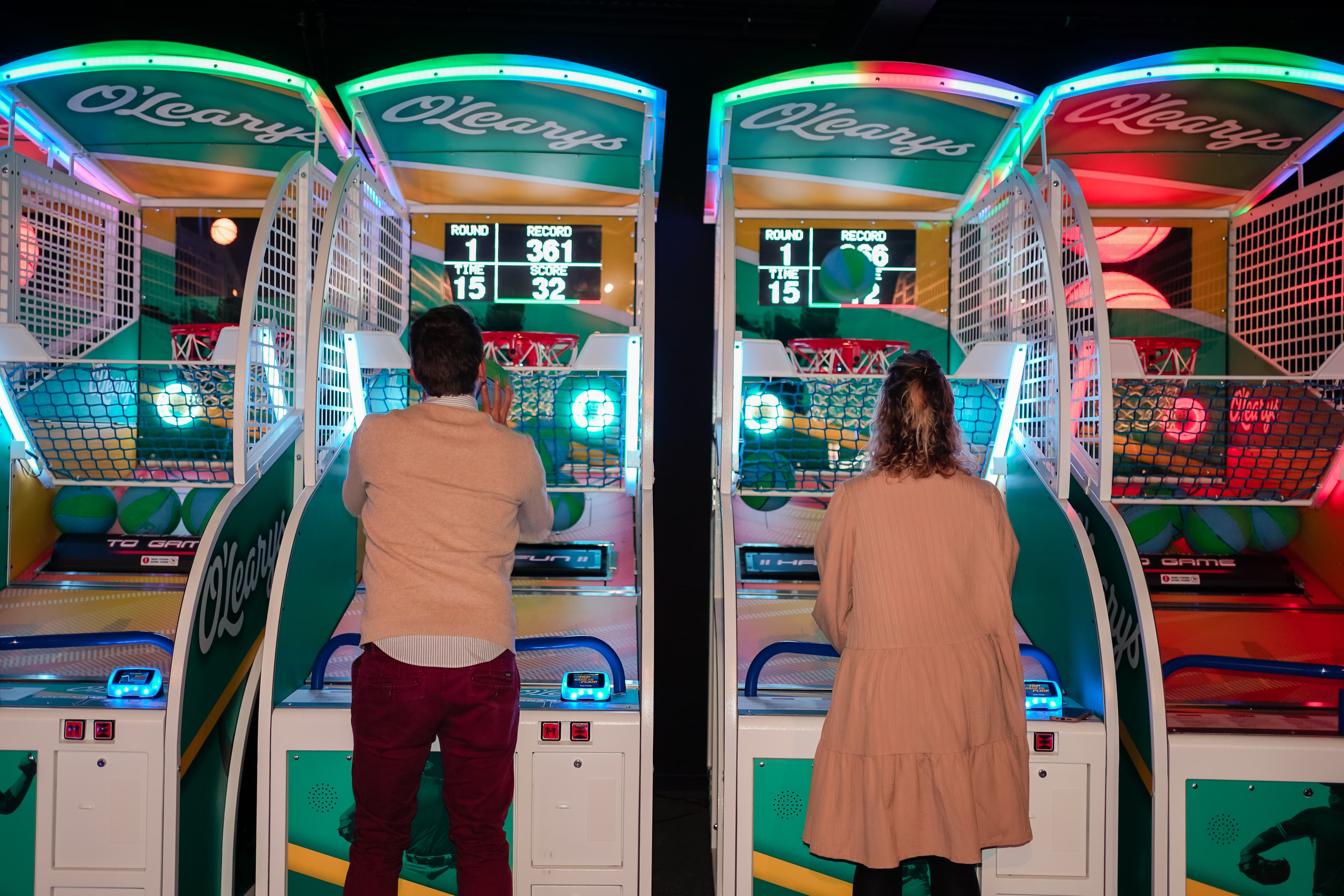 Twee mensen spelen arcadegame (basket) in de gamehal bij O'Learys